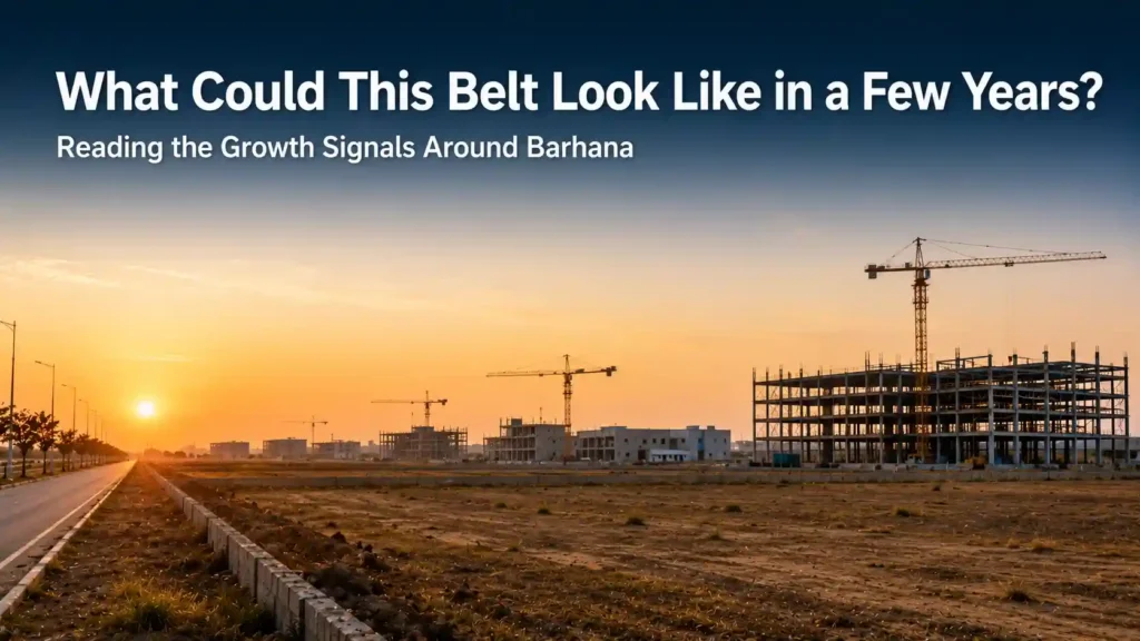 Construction cranes rising over open land at sunrise representing long-term growth potential near Barhana Industrial Area